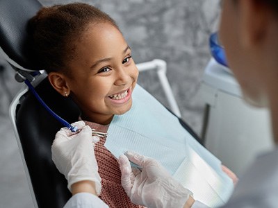 Dentist placing bib on smiling child