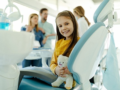 Child smiling while dentist and parents talk