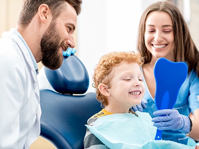 Child smiling in mirror after getting metal-free filling