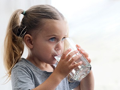 Little girl drinking glass of water after swallowing medication