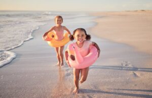 Two kids with floaties running on the beach